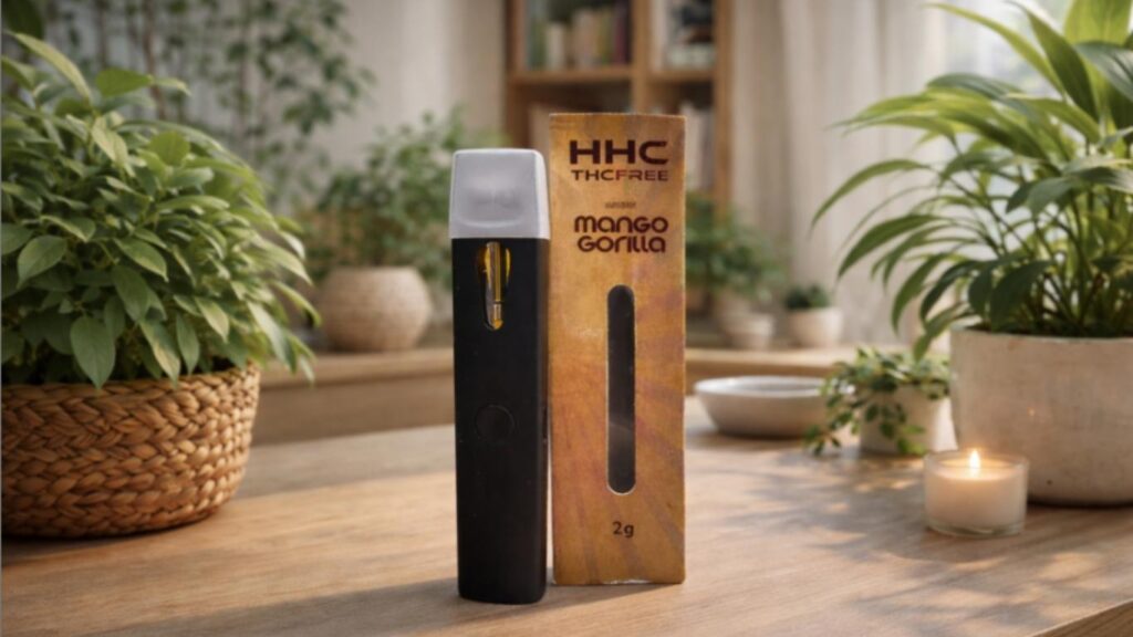 Vaporizador CBD Mango Gorilla apresentado numa mesa de madeira com plantas e vela num ambiente natural e relaxante de interior