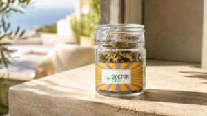 CBD Aveiro com frasco de flores CBD Doctor CBD apresentado numa varanda ou terraço luminoso, com vista desfocada ao fundo.
