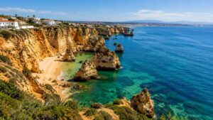 Vista panorâmica da costa algarvia com falésias douradas, mar azul-turquesa e praias ao longo da linha costeira, numa imagem sobre CBD no Algarve.